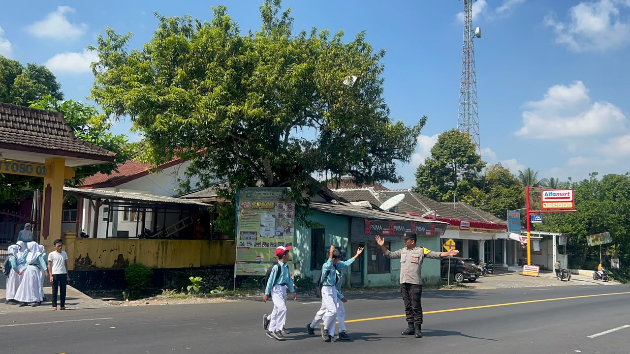 Personil Polsek Ranuyoso Bantu Seberangkan Pelajar di Jam Sibuk