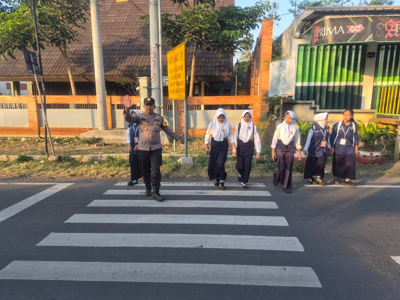 Terik Matahari Tak Surutkan Semangat Polisi Bantu Pelajar Menyeberang di Senduro
