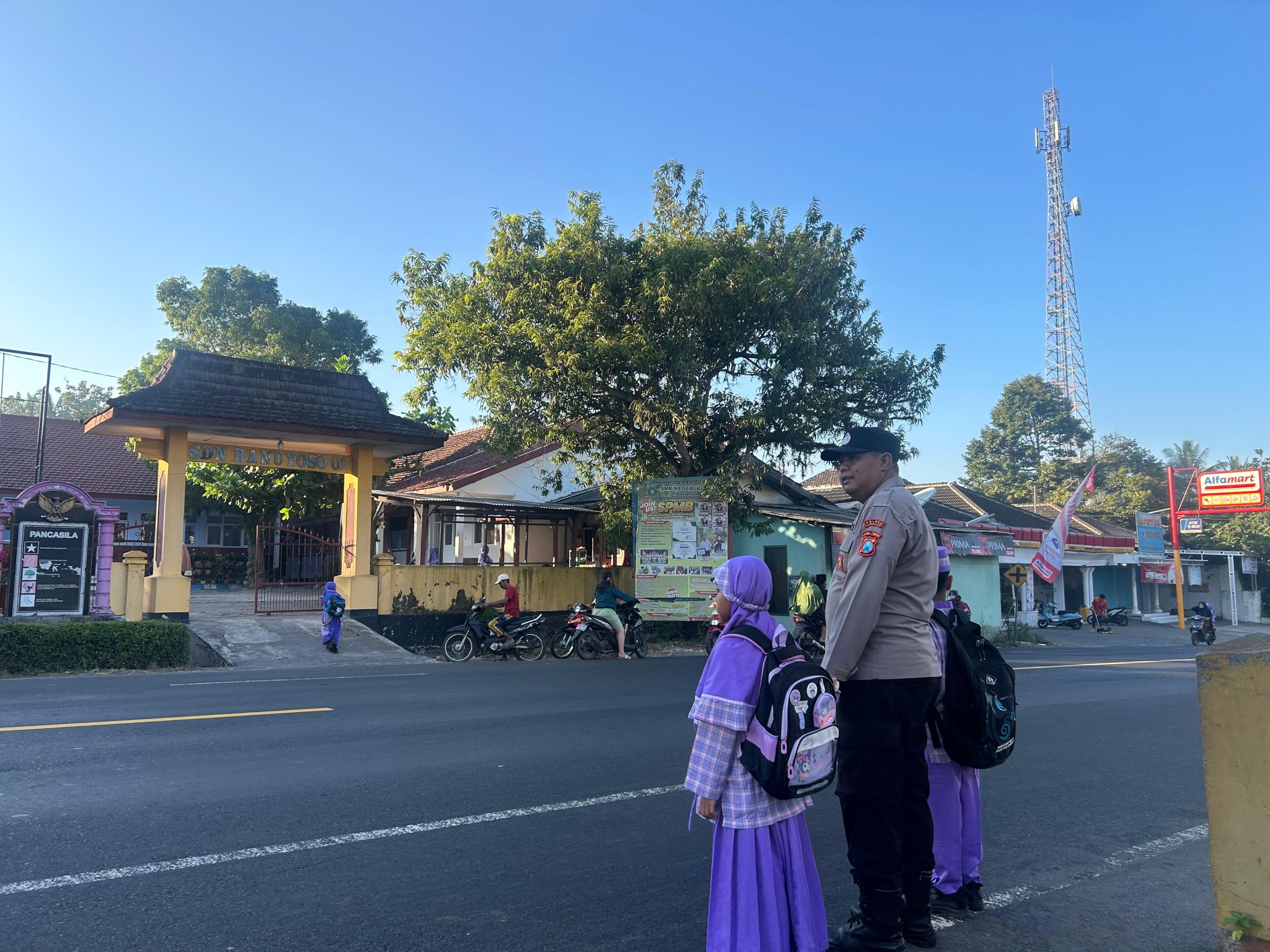 Personil Polsek Ranuyoso Bantu Seberangkan Pelajar di Jam Sibuk