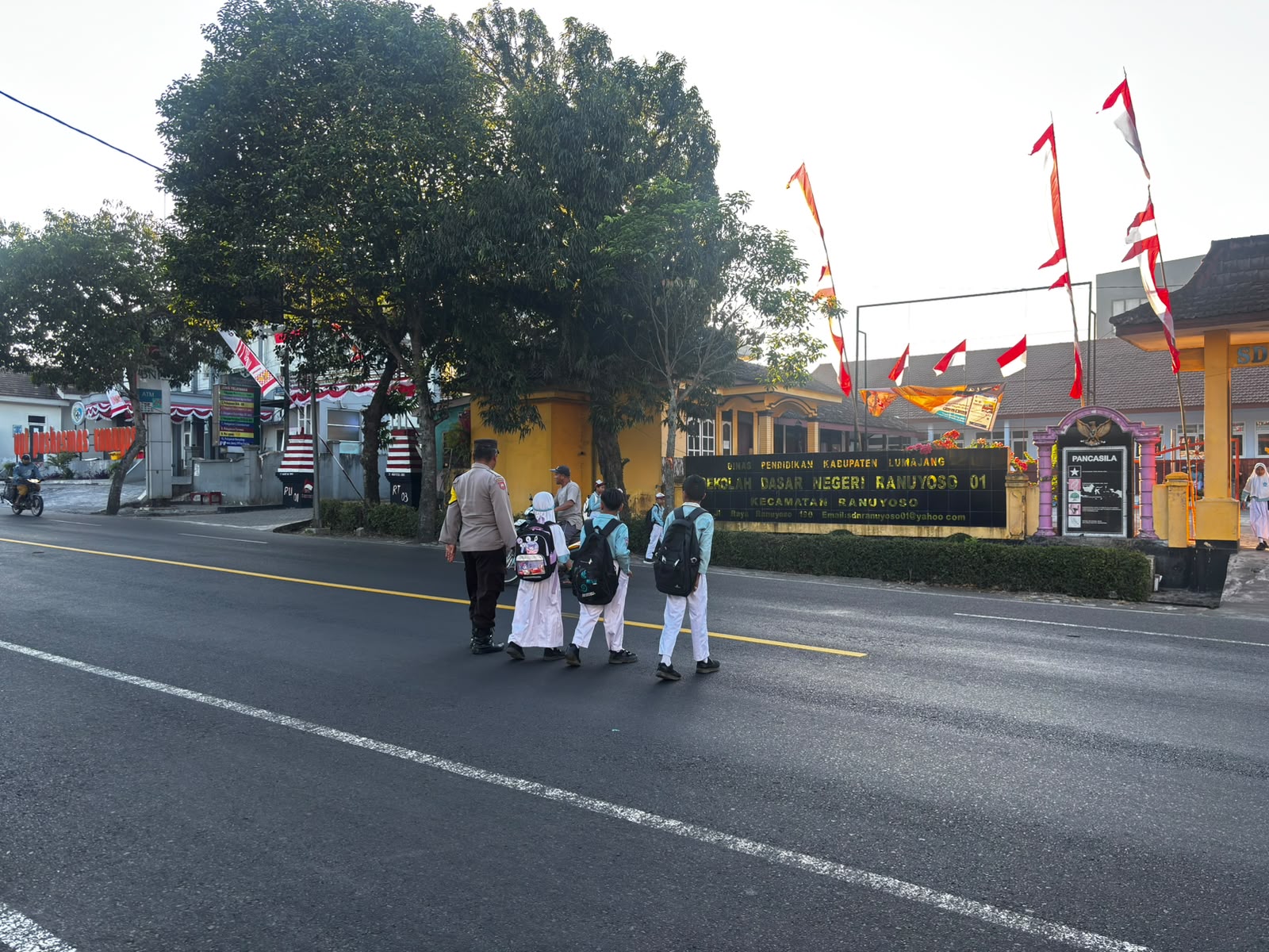 Personil Polsek Ranuyoso Bantu Seberangkan Pelajar di Jam Sibuk