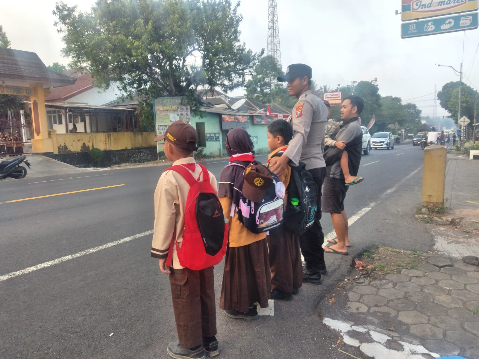 Personil Polsek Ranuyoso Bantu Seberangkan Pelajar di Jam Sibuk